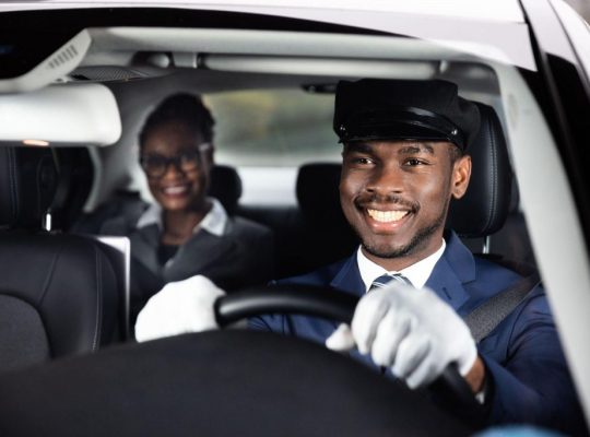 businesswoman-sitting-behind-happy-african-male-chauffeur-driving-car-1024x683